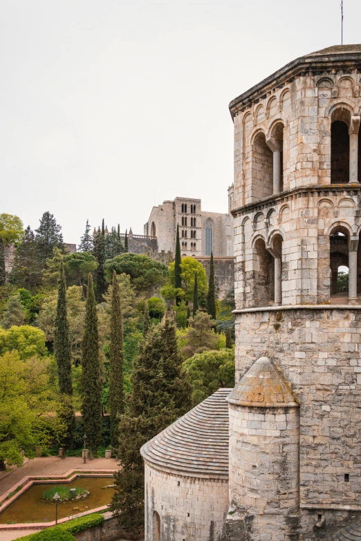 a tall tower with a clock on top of it, inspired by Dionisio Baixeras Verdaguer, romanesque, overlooking a valley with trees, exterior shot, round buildings in background, close-up from above