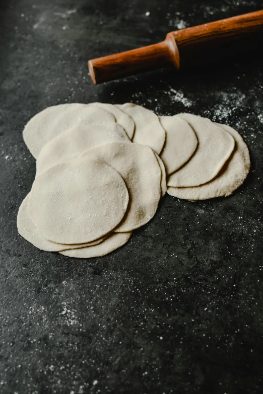 a pile of uncooked dough next to a rolling pin, inspired by Li Di, unsplash, mingei, berets, tacos, sleek round shapes, thumbnail