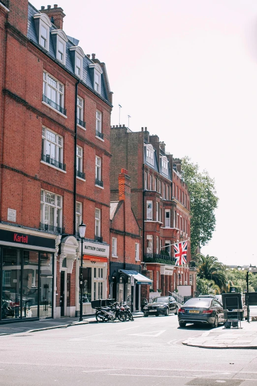 a car driving down a street next to tall buildings, by Nina Hamnett, pexels contest winner, art nouveau, english village, red bricks, exterior view, paul davey