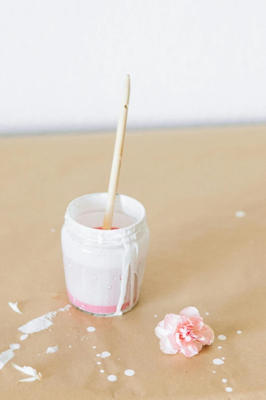 a jar of paint sitting on top of a table, white and pink, detailed product image, pouring, flower power