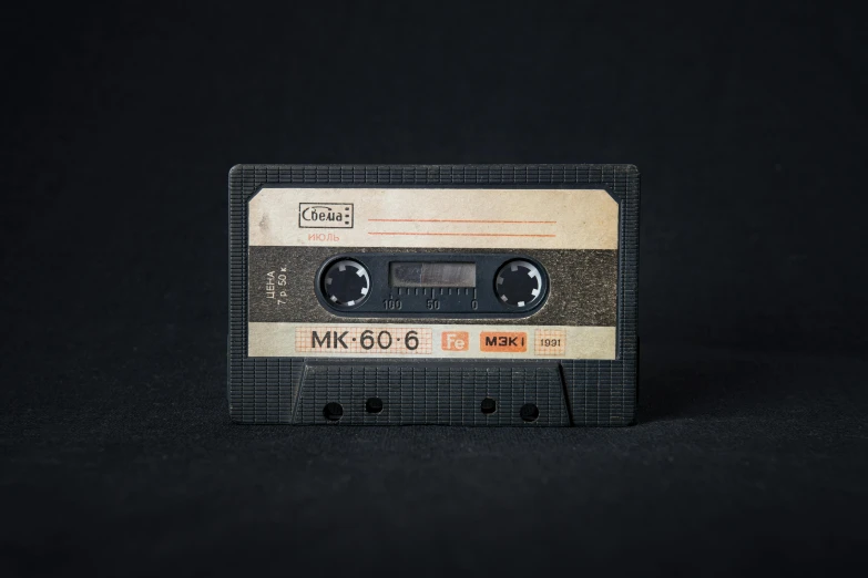 a close up of a cassette on a black background, an album cover, by Matthias Stom, unsplash, 8k archival print, realistic old photograph, magnetic, on a gray background