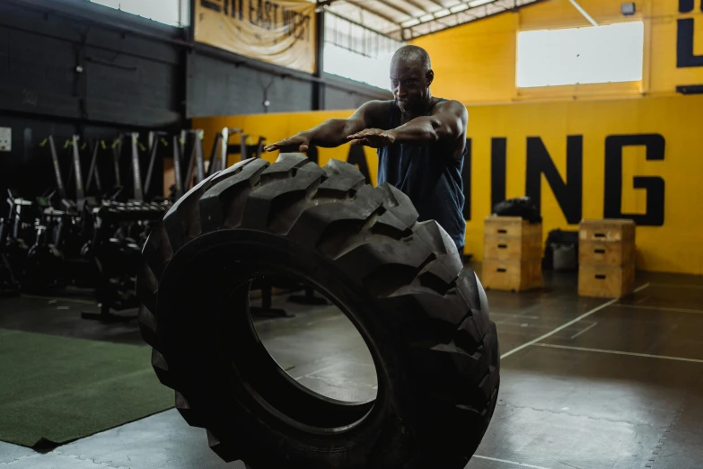 a man holding a large tire in a gym, a portrait, pexels contest winner, yellow charcoal, profile image, thumbnail, pouncing