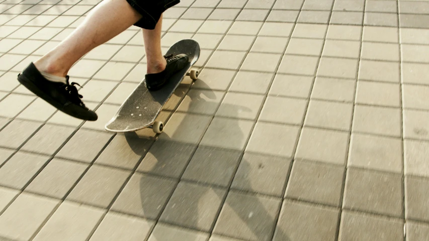 a person riding a skateboard on a sidewalk, unsplash, photorealism, tiles, square lines, low quality photo, thumbnail