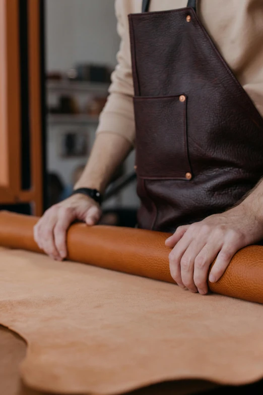 a man standing next to a roll of leather, trending on pexels, arbeitsrat für kunst, back of hand on the table, thumbnail, bakery, smooth color