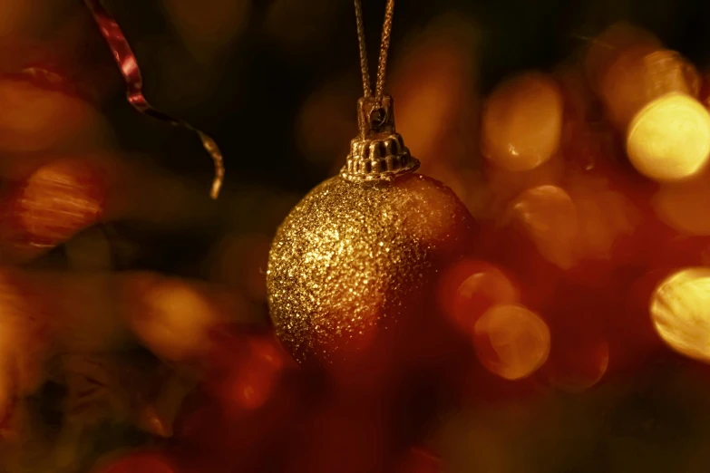 a christmas ornament hanging from a christmas tree, by Adam Marczyński, pexels contest winner, gold dappled lighting, thumbnail, shot on sony a 7, golden glow