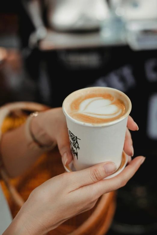 a close up of a person holding a cup of coffee, daily specials, aussie baristas, light tan, mild