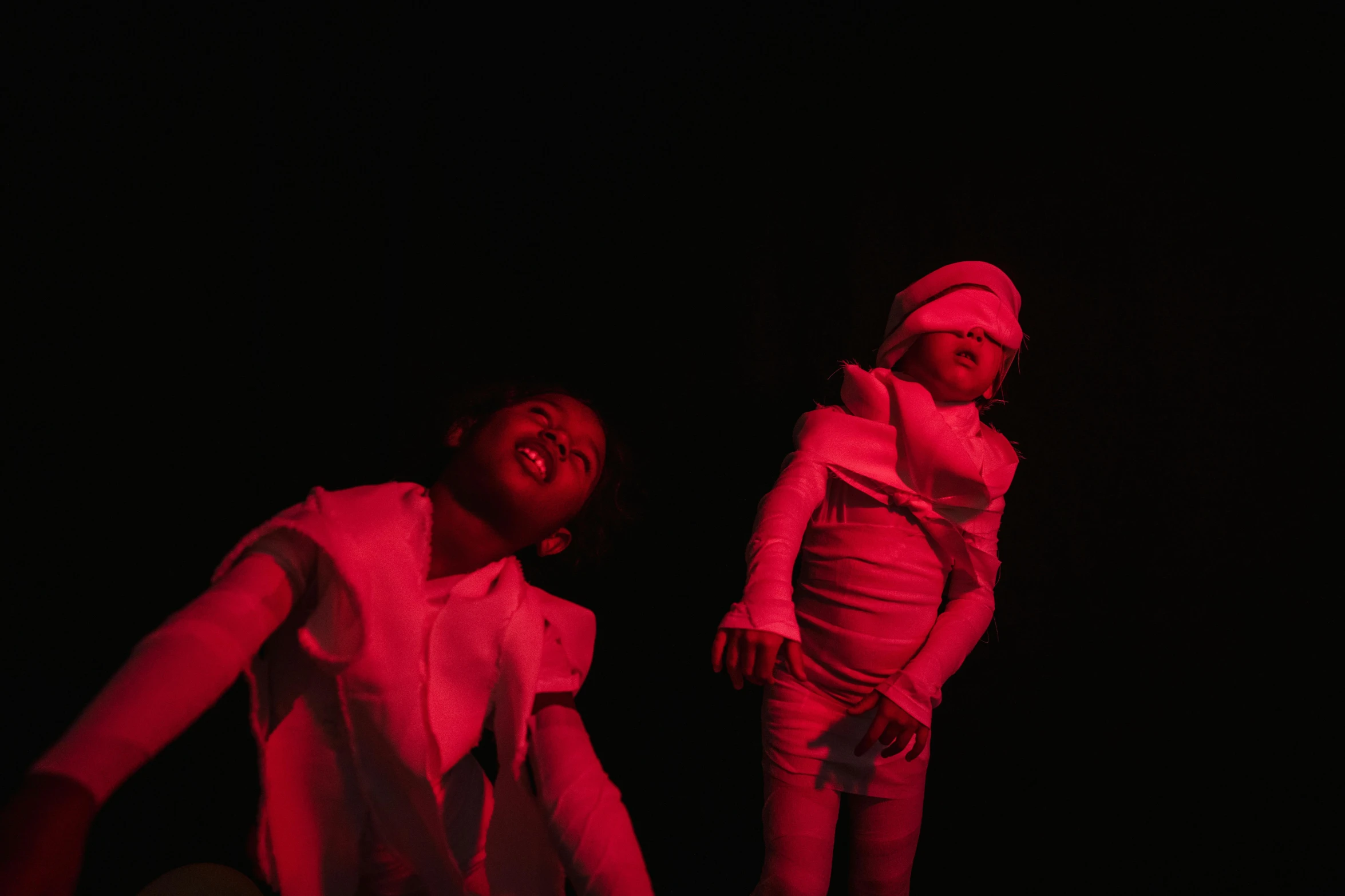 a couple of people that are standing in the dark, inspired by Carrie Mae Weems, unsplash, figuration libre, performing on stage, kids, red and white lighting, pose 4 of 1 6