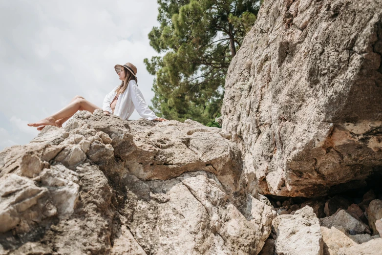 a woman sitting on top of a large rock, trending on pexels, al fresco, white, avatar image