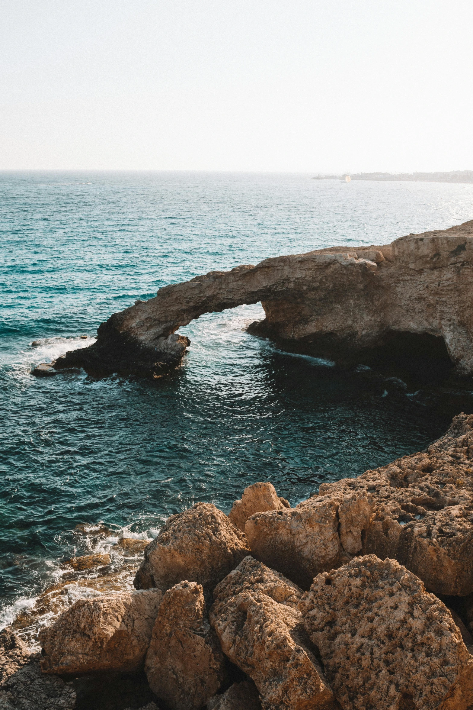 a man standing on top of a rocky cliff next to the ocean, cyprus, bridge over the water, massive arch, top selection on unsplash