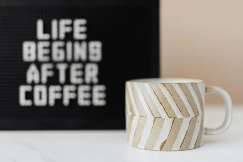 a coffee mug sitting on top of a table, a stipple, inspired by Stephen Little, trending on unsplash, graffiti, jar on a shelf, white and gold kintsugi, light box, striped