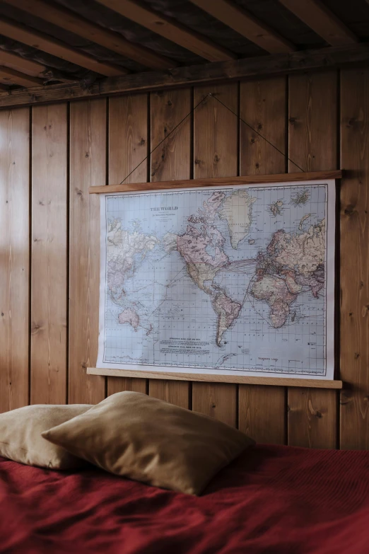 a bedroom with a bed and a map on the wall, inspired by Wilhelm Marstrand, unsplash, beautiful wooden frame, hanging silk scroll, uk, placed in a living room