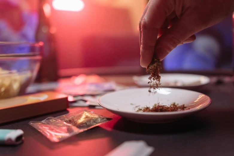 a close up of a plate of food on a table, by Julia Pishtar, pexels contest winner, process art, smoking weed, nightlife, spices, back of hand on the table