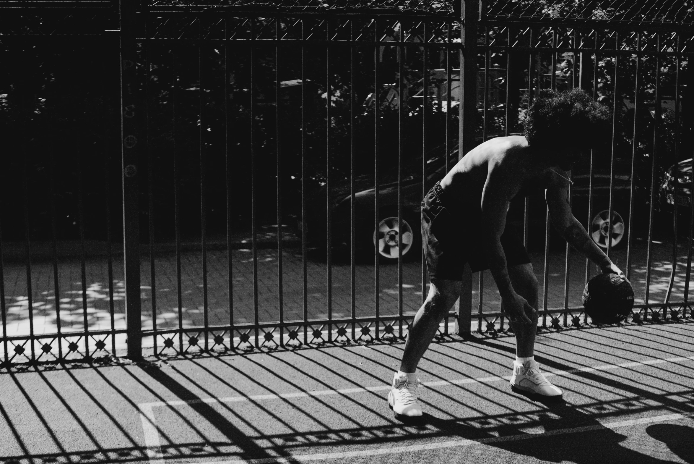 a man riding a skateboard down a sidewalk next to a fence, a black and white photo, curly afro, playing tennis, sun and shadow, streets of new york