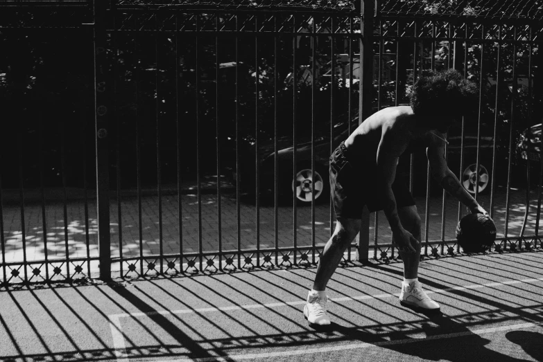 a man riding a skateboard down a sidewalk next to a fence, a black and white photo, curly afro, playing tennis, sun and shadow, streets of new york