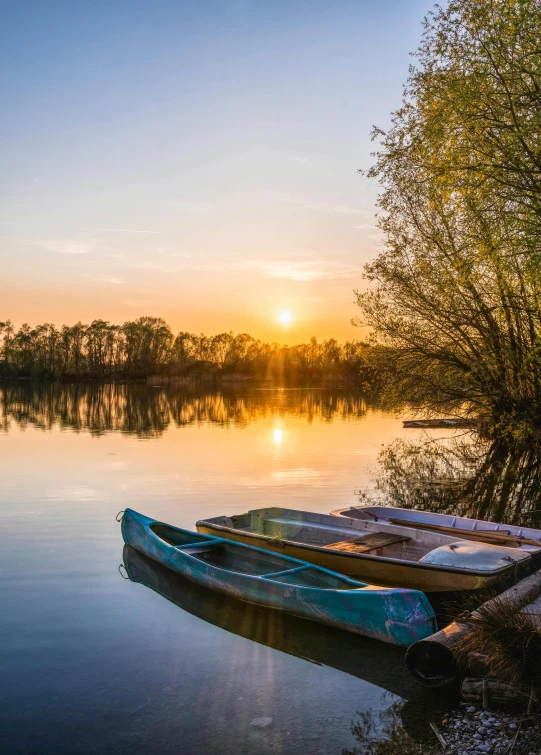 a couple of boats sitting on top of a lake, by Antoni Brodowski, at sunrise in springtime, golden hour photograph, photograph, wide image