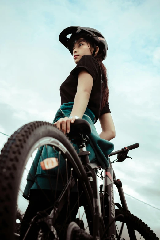 a woman standing next to a bicycle with a helmet on, unsplash, looking to the sky, malaysian, rectangle, wheelchair