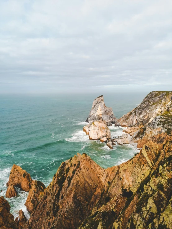 a person standing on top of a cliff next to the ocean, portugal, profile image