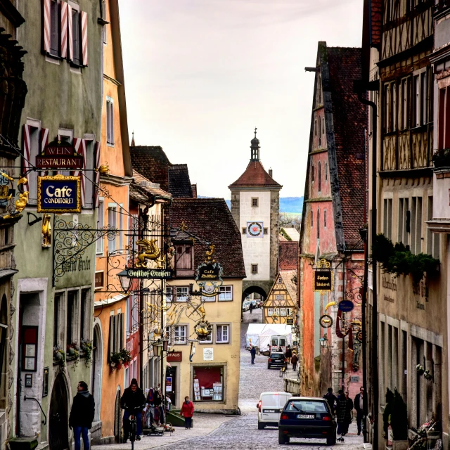 a narrow cobblestone street with a clock tower in the background, by Juergen von Huendeberg, pexels contest winner, renaissance, thatched roofs, full colored, square, soft - warm