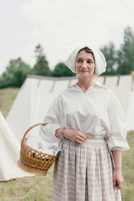 a woman standing in a field holding a basket, pexels contest winner, renaissance, white uniform, encampment, laundry hanging, portrait image