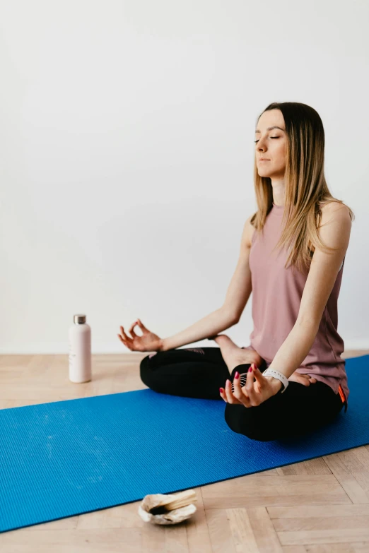 a woman sits on a yoga mat and meditates, by Rachel Reckitt, holding a bottle, high-quality photo, profile image, wētā fx