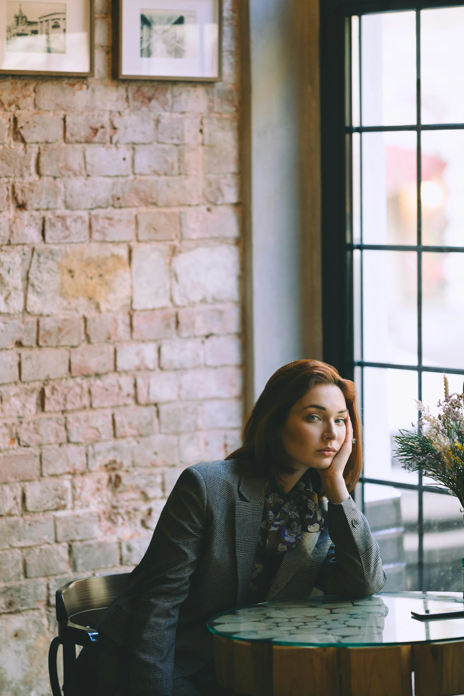 a woman sitting at a table in front of a window, a portrait, trending on unsplash, eleanor tomlinson, girl in suit, sitting alone in a cafe, waiting behind a wall