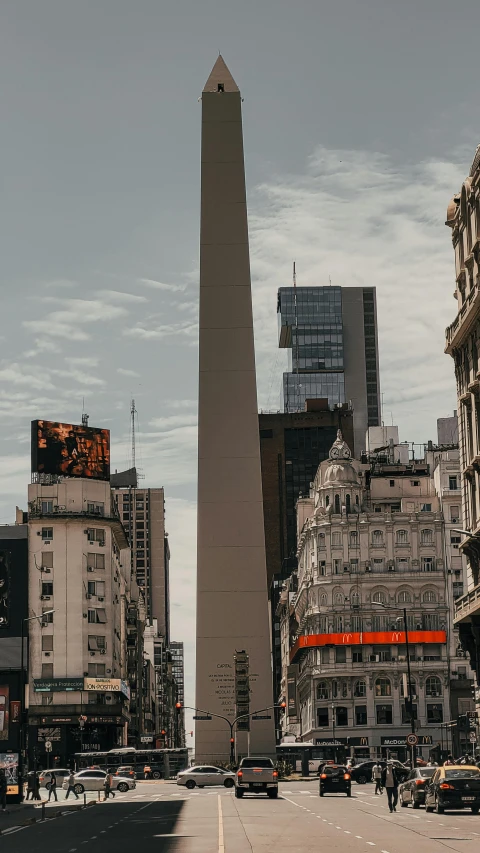 a city street filled with lots of traffic and tall buildings, by Matteo Pérez, pexels contest winner, obelisk, neo-andean architecture, gif, neoclassical architecture