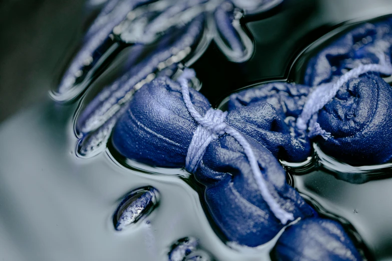 a pair of blue shoes floating on top of a body of water, a macro photograph, inspired by Yves Klein, unsplash, process art, carved soap, floggers, high quality photo, made of liquid purple metal