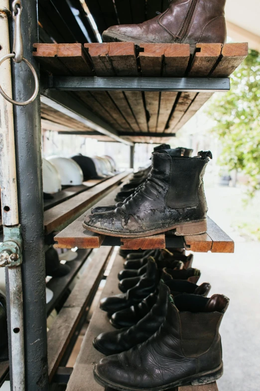 a bunch of shoes that are on a shelf, by Jessie Algie, unsplash, standing on mad max panzer tank, rustic and weathered, black leather boots, sitting on a store shelf