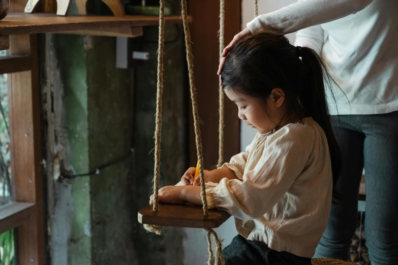 a little girl that is sitting on a swing, pexels contest winner, interactive art, on a wooden tray, a young asian woman, carefully crafted, daughter