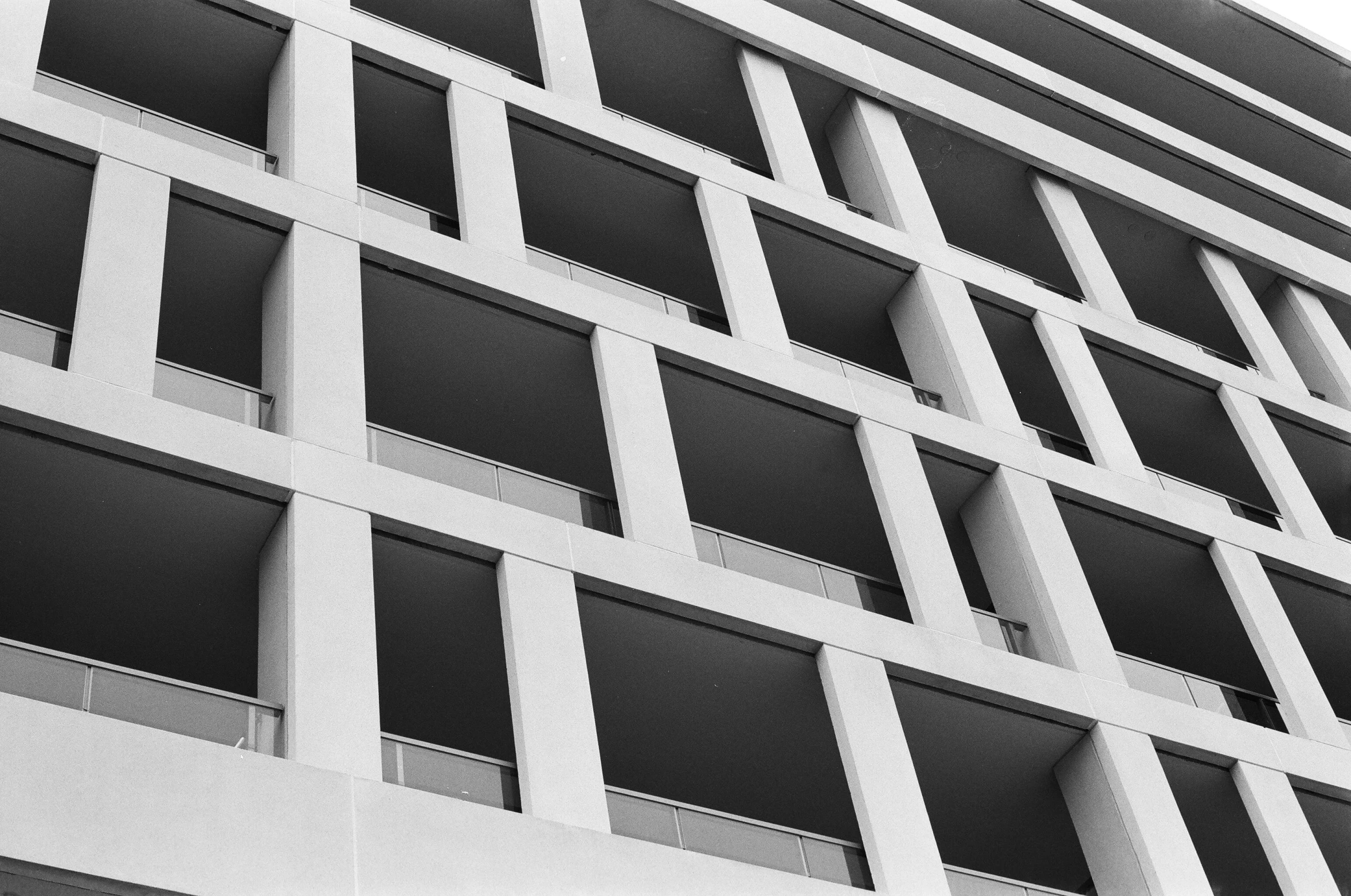 a black and white photo of a tall building, inspired by David Chipperfield, unsplash, brutalism, balconies, white concrete, squares, uploaded