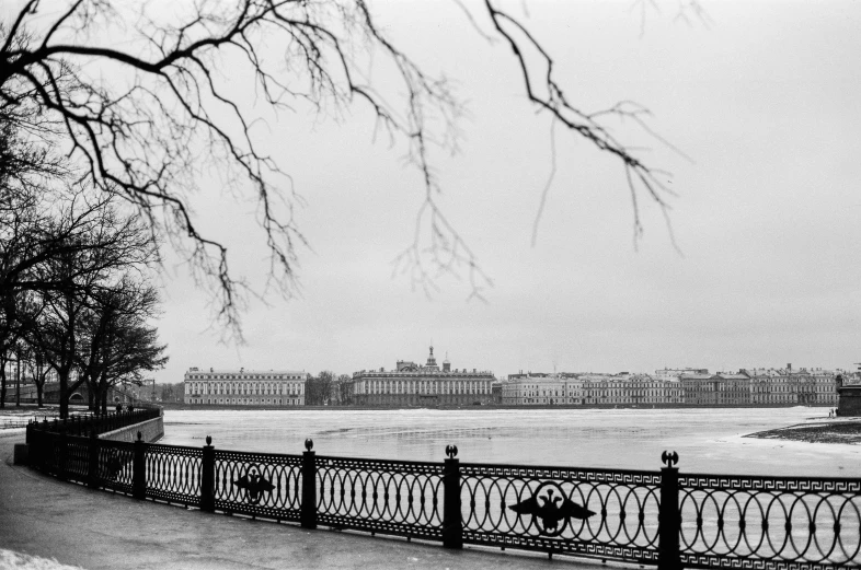 a black and white photo of a person sitting on a bench, inspired by Henri Cartier-Bresson, pexels contest winner, royal palace near the lake, russian city, tri - x pan stock, all buildings on bridge