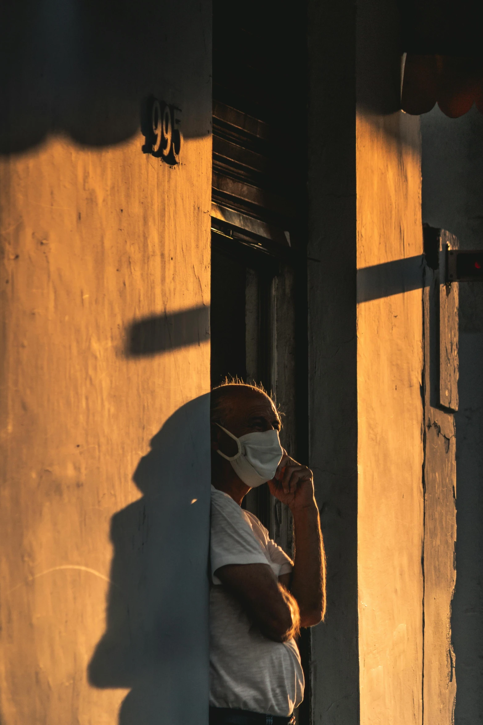 a woman wearing a face mask talking on a cell phone, by Peter Churcher, pexels contest winner, sunset. light shadow, manila, leaning on door, a man