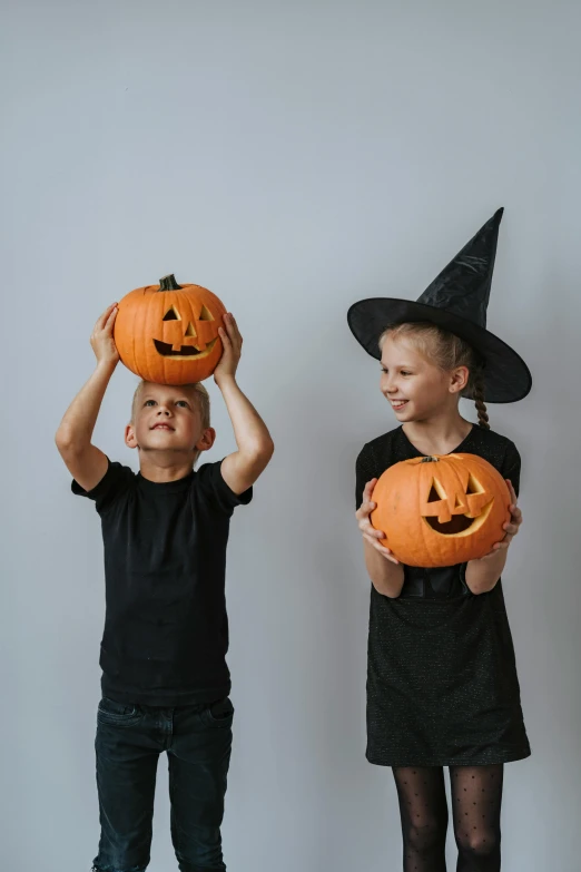 three children in halloween costumes holding pumpkins, pexels contest winner, antipodeans, black pointed hat, medium shot of two characters, on a gray background, profile picture