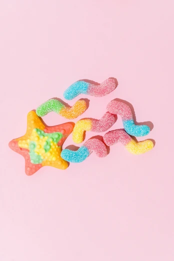 a pile of gummy bears sitting on top of a pink surface, a microscopic photo, starfish pose, rainbow trail, full product shot, swirly