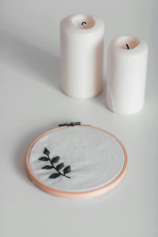 a close up of a embroidery on a table, inspired by Master of the Embroidered Foliage, trending on pexels, white candles, minimalist photo, white backdrop, 8 5 mm photograph