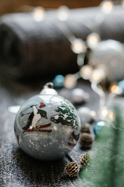 a close up of a christmas ornament on a table, inspired by Ernest William Christmas, graffiti, birds, grey and silver, natural soft light, thumbnail