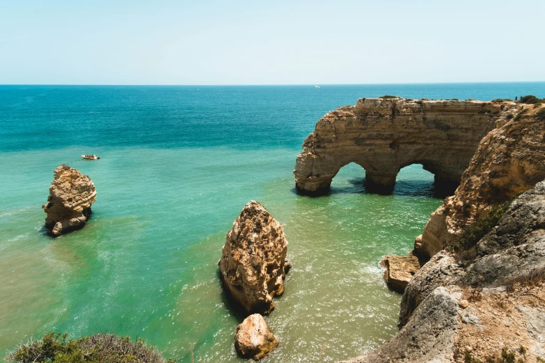 a body of water that has some rocks in it, a tilt shift photo, pexels contest winner, renaissance, massive arch, portugal, thumbnail, turquoise horizon