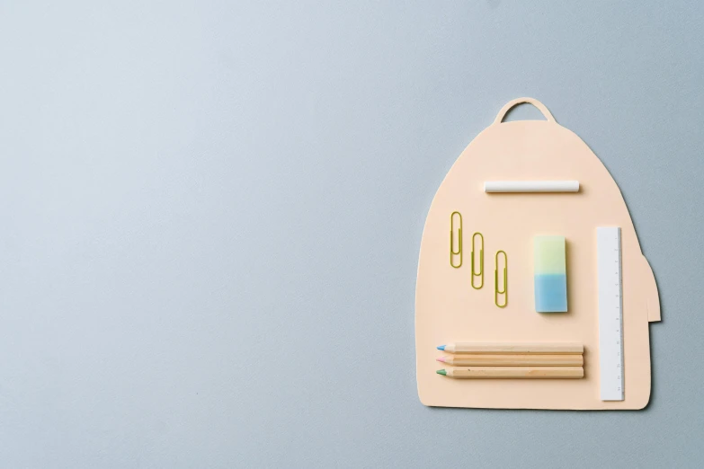 a close up of a piece of paper with pencils and paper clips, an album cover, trending on pexels, minimalism, a backpack, in pastel shades, rounded shapes, no - text no - logo