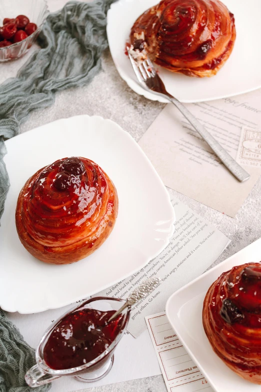 a table topped with three white plates filled with pastries, inspired by Richmond Barthé, unsplash, baroque, crimson single french braid bun, jelly, background image, made of glazed