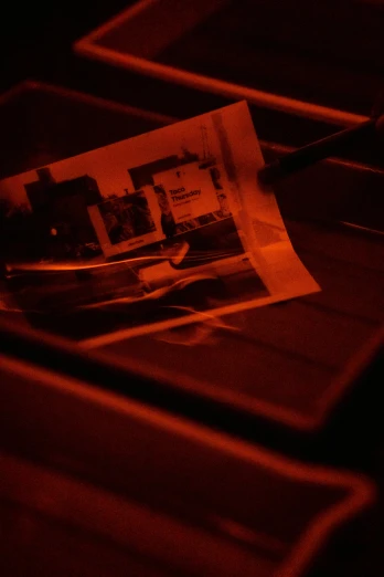 a pair of scissors sitting on top of a table, a picture, inspired by Nan Goldin, holography, red and orange glow, printed page, pinhole photo, red monochrome
