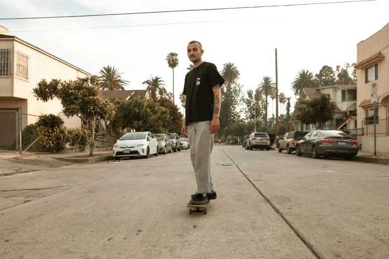 a man riding a skateboard down a street, by Winona Nelson, mac miller, wearing pants and a t-shirt, portrait mode photo, brian pulido