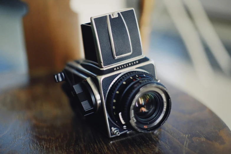 a camera sitting on top of a wooden table, by Romain brook, unsplash, photorealism, hasselblad 500c, film photo from 1970s, medium format. soft light, a high angle shot