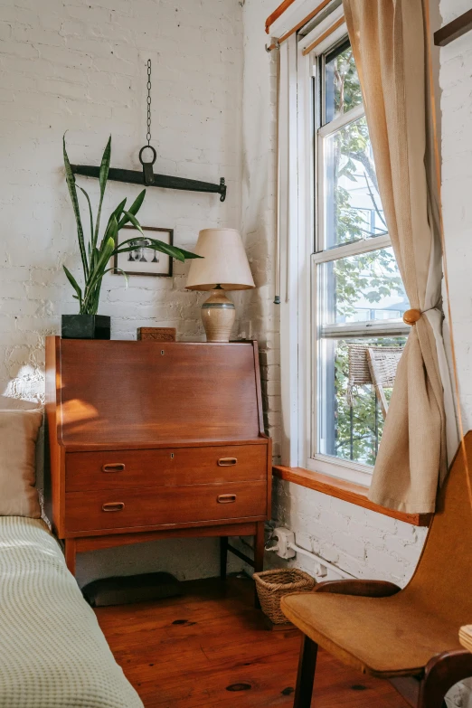 a bed sitting in a bedroom next to a window, inspired by Constantin Hansen, unsplash, wooden cabinet, profile image, lush and green, small library