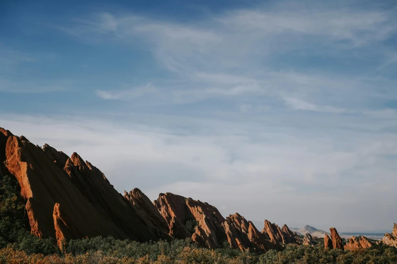 a couple of people standing on top of a mountain, by Lee Loughridge, unsplash contest winner, red sandstone natural sculptures, background image, asymmetrical spires, in a row