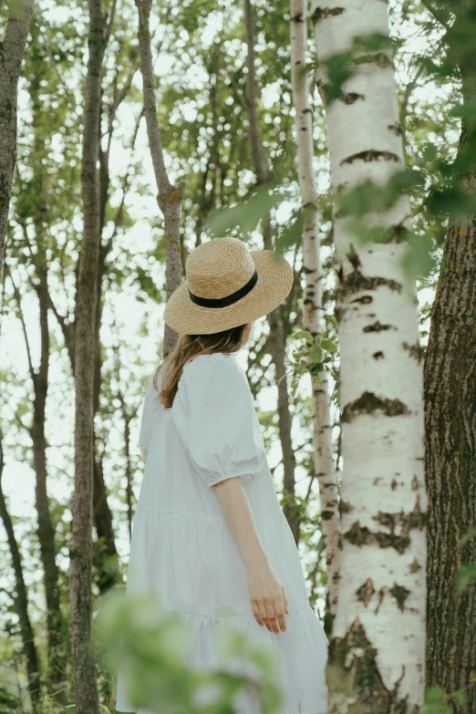 a woman in a white dress and hat standing in the woods, pexels contest winner, wearing a linen shirt, birch, curated collections, facing away