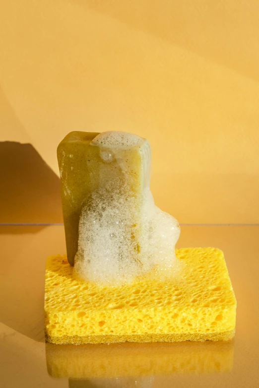 a yellow sponge sitting on top of a yellow surface, an abstract sculpture, inspired by Konstantinas Ciurlionis, soap, covered in salt, jade sculpture, full product shot