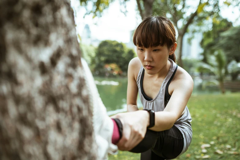a woman squatting next to a tree in a park, inspired by Wen Jia, pexels contest winner, happening, boxing stance, working out, low detail, up to the elbow