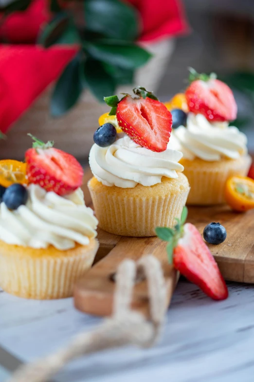 a couple of cupcakes sitting on top of a wooden cutting board, fresh fruit, 👅 👅, cream, holiday