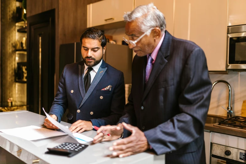 a couple of men standing next to each other in a kitchen, unsplash, hurufiyya, wearing a suit and glasses, working, dressed in a jodhpuri suit, thumbnail