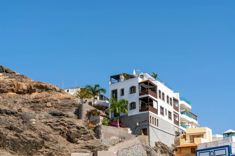 a large white building sitting on top of a hill, by Daniel Lieske, pexels contest winner, summer street near a beach, brown, diego fernandez, built on a steep hill